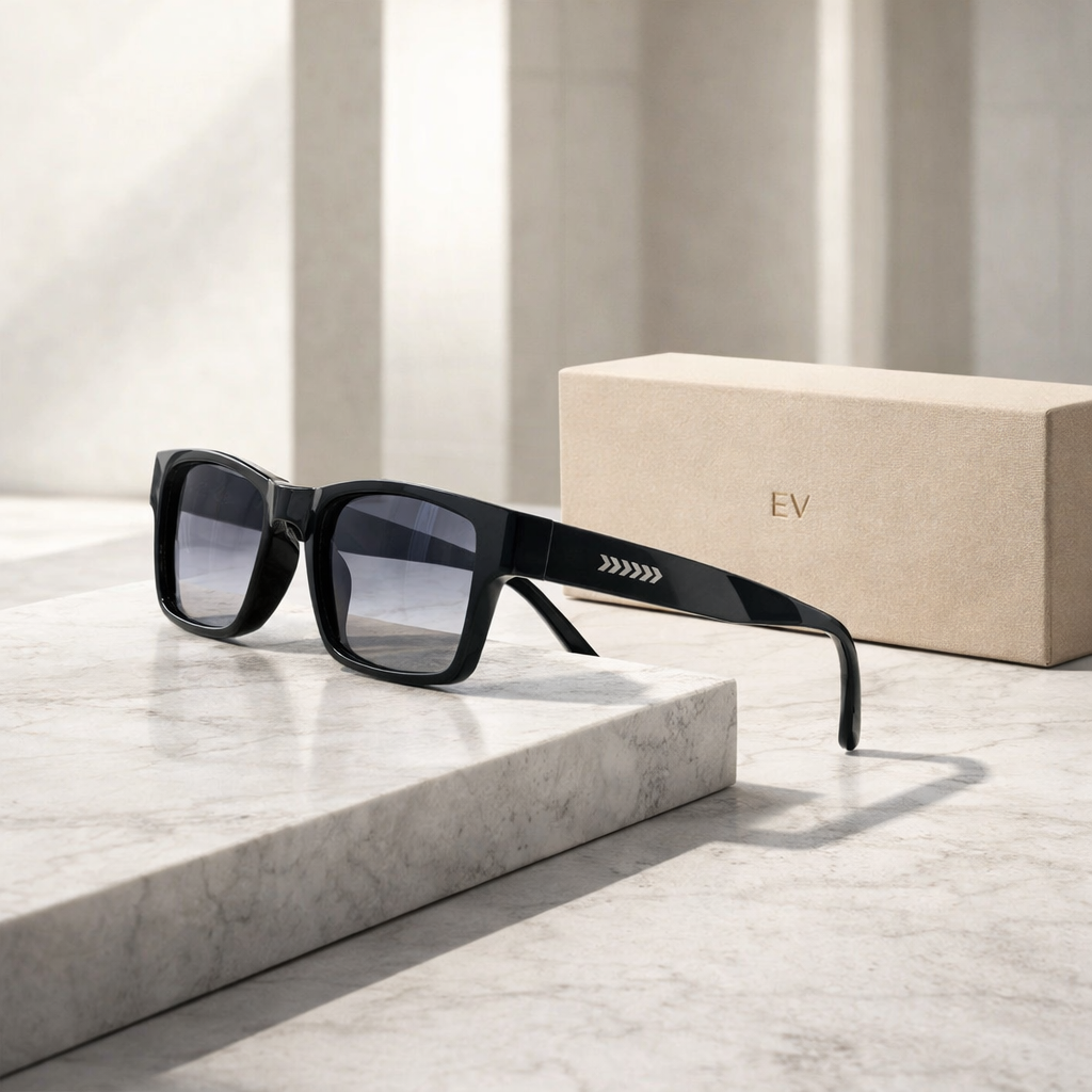Black sunglasses with a logo on a marble surface next to a beige box.